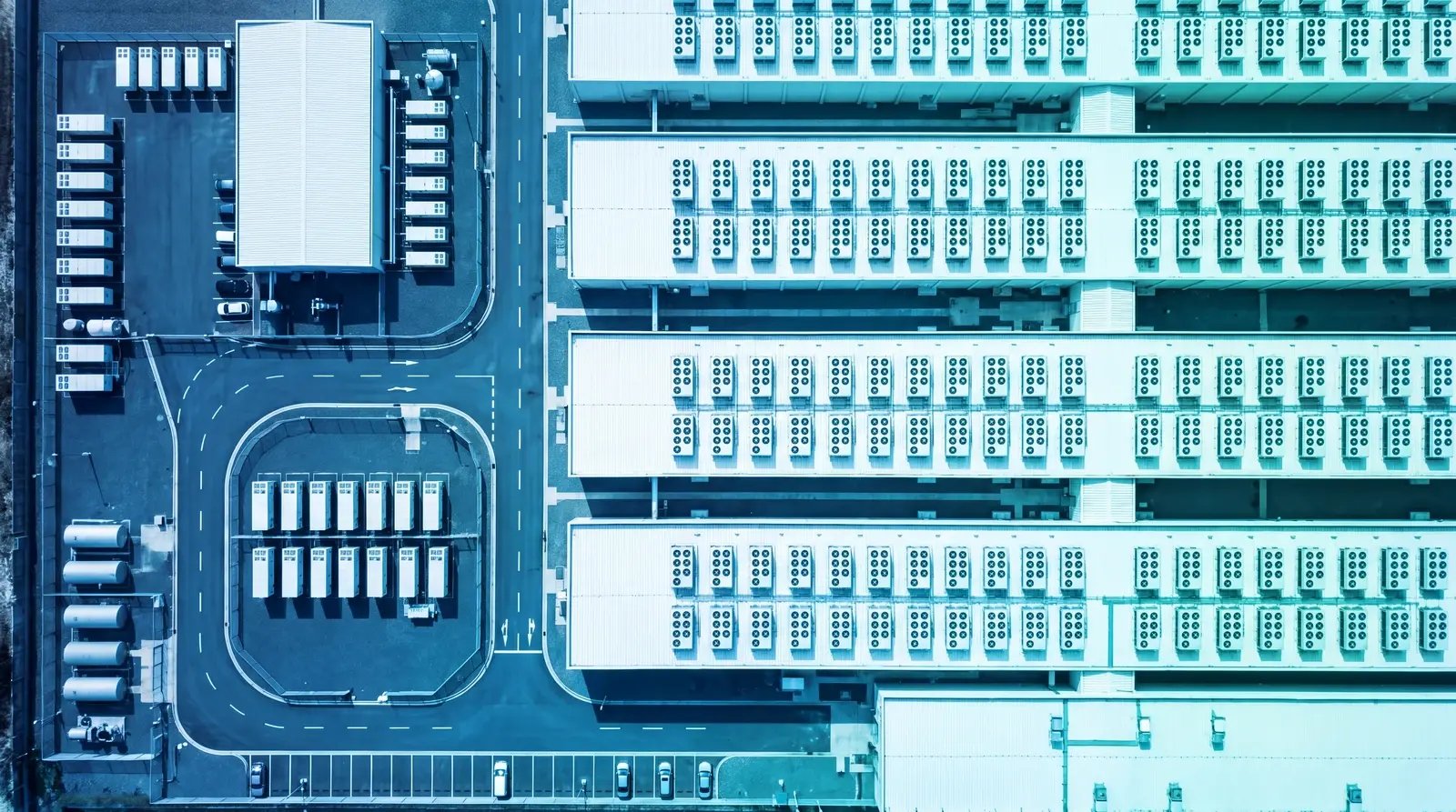 Aerial view straight down on data center halls with rows of rooftop cooling units, in a cool blue-teal gradient