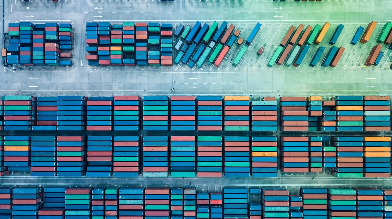 Aerial view of a container yard where ordered rows fray into uncounted sprawl, a metaphor for over-permissioned AI agents