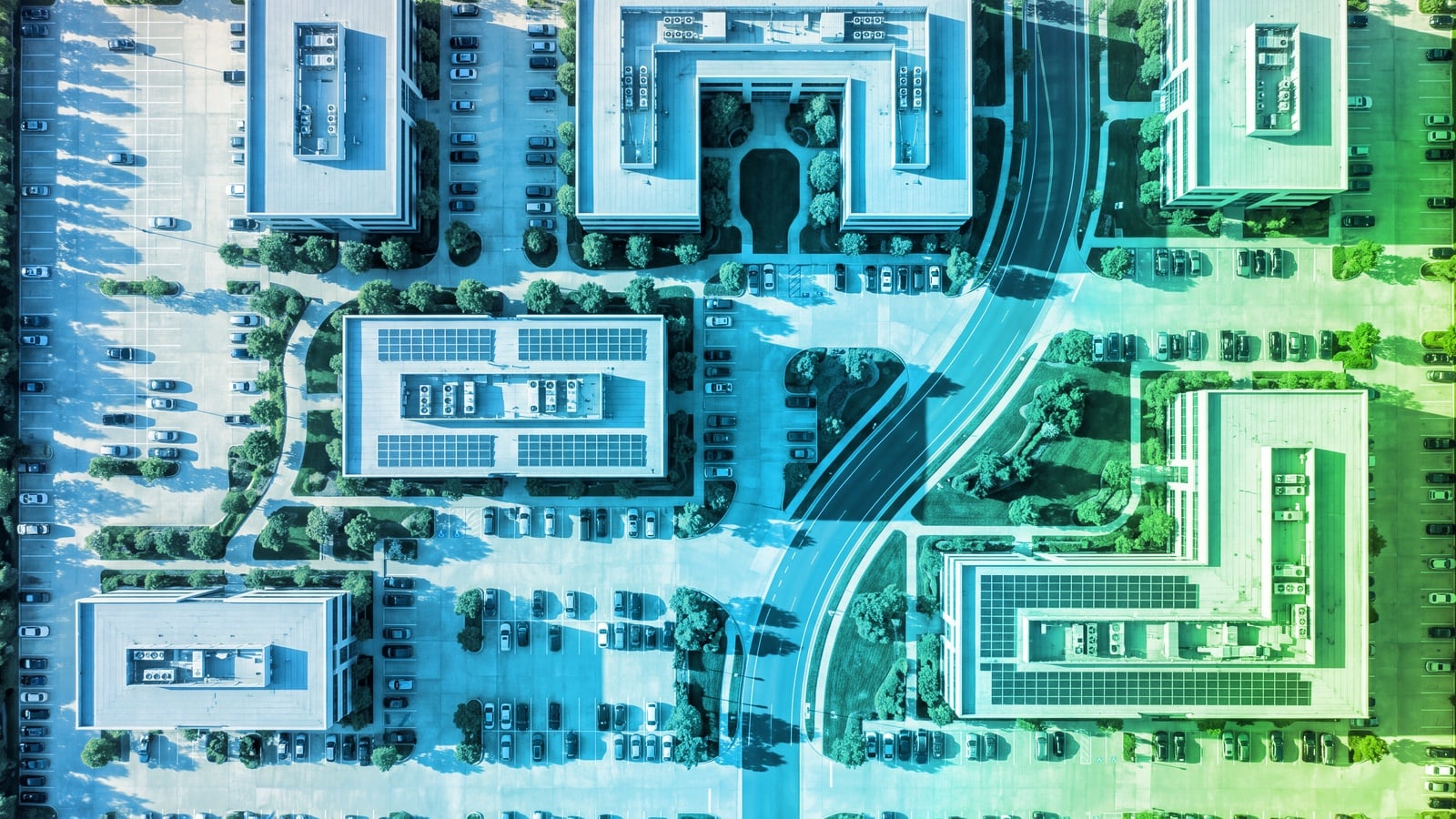 Straight-down aerial view of a corporate office park in long afternoon shadows, tinted in a blue-to-green gradient